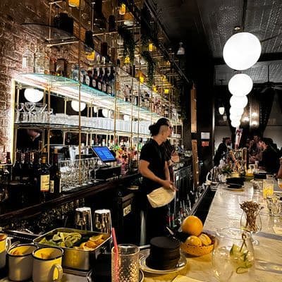 Dimly lit dining room and marble bar at Little More in Tribeca